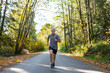 © Rob and Julia Campbell/Stocksy - Fit man running hard on road in autumn or fall.