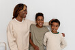 © Bisual Studio/Stocksy - Happy single mom with sons against gray wall