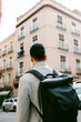 © Jimena Roquero/Stocksy - Back of young stylish man carrying a backpack in sunlight in the city