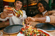 © Jimena Roquero/Stocksy - Friends sharing delicious vegetarian pizza in restaurant