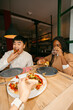 © Jimena Roquero/Stocksy - Friends sharing pizza in restaurant