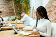 © Jimena Roquero/Stocksy - Freelance woman taking notes and working on tablet in modern workspace