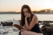 © Lucas Ottone/Stocksy - Woman reading a book by the sea