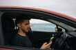 © Pedro Merino/Stocksy - Man using the mobile in the car parked in front of the sea