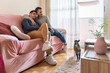© Luis Velasco/Stocksy - Cute Gay Couple Watching TV On The Couch.