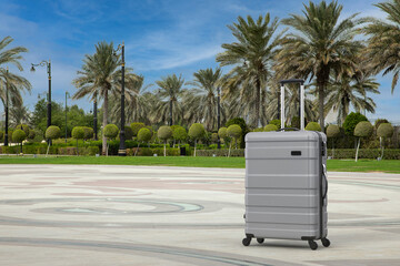 Aufkleber - Travel Holiday Vacation Concept. Modern Luxury Plastic Gray Suitcase on an Empty City Street with Palm Trees. 3d Rendering