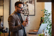 © zorandim75 - Handsome young businessman with glasses, using a laptop and a smart phone while working in the cafe