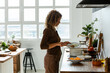 © Momento Estudio/Stocksy - Smiling woman pouring rice into pan in kitchen