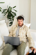 © Alba Vitta/Stocksy - Man listening to music on laptop headphones at home