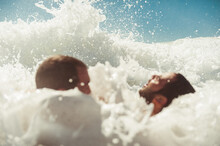 Two Friends Having Fun Inside Sea Waves Foam