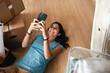 © Luis Herrera/Stocksy - woman lying on the floor with home moving boxes