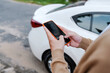 © Marc Tran/Stocksy - Man holding mobile phone next to door of his car in the street