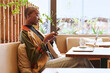 © Ivan Gener/Stocksy - Woman texting on her phone in a cafe