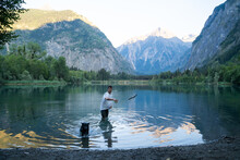Man Playing With Dog In Mountain Lake