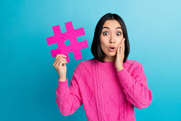 Poster - Portrait of impressed filipino person arm touch cheekbone hold paper hashtag isolated on blue color background