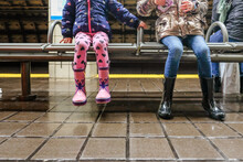 Closeup Of Two Girls Sitting On Bench Inside Train Station Waiting