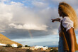 © Michela Ravasio/Stocksy - Woman pointing to the rainbow