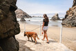 © Luis Herrera/Stocksy - Woman walking her dog at the beach