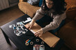 © Pedro Merino/Stocksy - Young woman making an album with polaroid photos at home