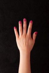 Wall Mural - Female hand with beautiful manicure - viva magenta, pink nails on dark black background