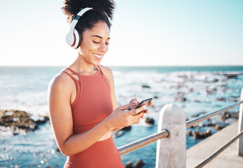 Poster - Black woman at beach, headphone and phone with fitness, runner listening to music for sports motivation. Happy, streaming online with podcast or radio, smartphone and running by sea with calm outdoor