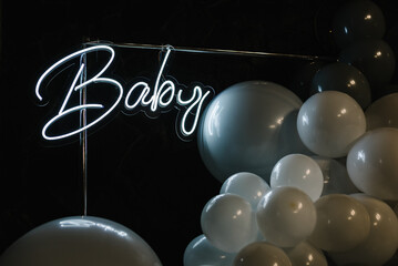 Birthday decorations - balloons for little baby party on a wall background. Celebration baptism concept. Photo booth with decor shiny and led strips with text Baby. Place for congratulations. Lights.