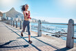 Woman running at ocean promenade for fitness, energy and strong body in Cape Town. Female runner, sports person and athlete at seaside for marathon, cardio exercise and healthy summer workout in sun