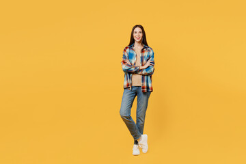 Poster - Full body cheerful happy confident young smiling woman wear blue shirt beige t-shirt look camera hold hand crossed folded isolated on plain yellow background studio portrait. People lifestyle concept