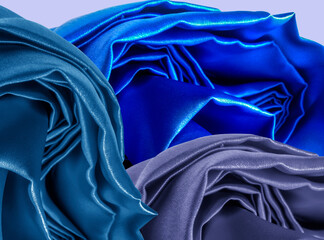 closeup of folds in blue satin fabric on blue background studio. blue silk fabric