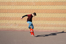Young Boy Skateboarding On Ramp In A City Park In Sunny Day