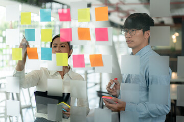 Poster - Two business executive team holding and taking notes keyword on board wall to brainstorm about a new business project for planning marketing plan together in the office