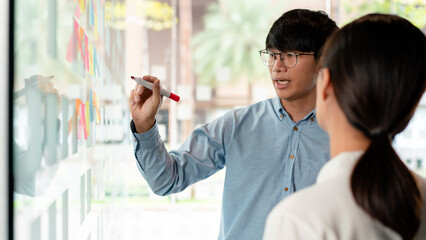 Poster - Two business executive team holding and taking notes keyword on board wall to brainstorm about a new business project for planning marketing plan together in the office