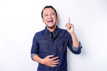 Starving Asian man wearing blue shirt pointing at the copy space on top of him, isolated by white background