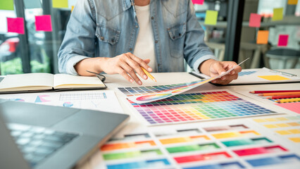 Poster - Young creative graphic designer working on color selection and drawing on graphics tablet at workplace, Color swatch samples chart for selection coloring in inspiration to create new collection