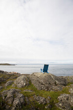 A Lawn Chair Sits Atop A Rock Outcrop Overlooking The Ocean On An Overcast Day In Victoria, British Columbia, Canada.