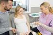 © auremar - pregnant woman with her husband visiting the doctor in clinic