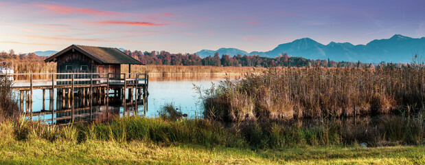 Fototapete - Scenic nature landscape. Sunrise on Chiemsee lake with vivid sky. Beautiful alpine sunset view on mountain lake and fishing hut near Rimsting at famous Chiemsee, Bavaria, Germany. nature background