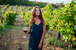 woman with a glass of red wine in a vineyard is going to drink wine