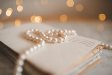 Stack Of Old Paper Letters With Elegant Pearl Necklace Over Glow Lights Closeup. Selective Focus.