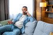 © Ivan - Serious thoughtful mobile phone user making telephone call from home, speaking on cell. Businessman, self employed specialist, remote worker sitting on couch, discussing work on cellphone