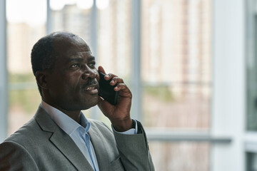 Poster - Side view of confident mature African American broker with mobile phone communicating with colleague or arranging appointment