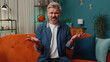 © Andrii Iemelianenko - What. Why. Middle-aged man raising hands in indignant expression asking reason of failure demonstrating disbelief irritation by troubles at home apartment. Mature guy in evening room sitting on sofa
