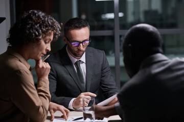 Aufkleber - Focus on serious broker analyzing financial document in front of two intercultural colleagues discussing graphic data at meeting