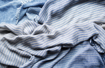 Background with draped blue gray cotton fabric, napkin, striped tablecloth or scarf, soft focus