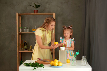 mother shows daughter how to make delicious and fresh lemonade in summer. cooking together in kitchen