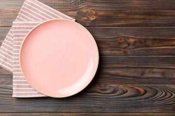 Wall Mural - Top view on colored background empty round pink plate on tablecloth for food. Empty dish on napkin with space for your design