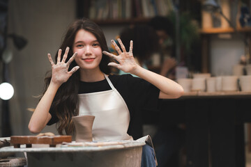 Wall Mural - happy smiling girl having fun to learning and work with craft art of clay hand-made workshop in ceramic studio, little ceramist enjoy in creative handcraft hobby with pottery artisan school class