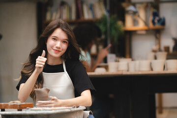 Wall Mural - happy smiling girl having fun to learning and work with craft art of clay hand-made workshop in ceramic studio, little ceramist enjoy in creative handcraft hobby with pottery artisan school class