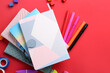 © Pixel-Shot - Stack of notebooks and different stationery on red background