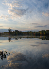 Wall Mural - A dramatic sky reflected in the calm surface of a small Northwoods lake at sunrise.